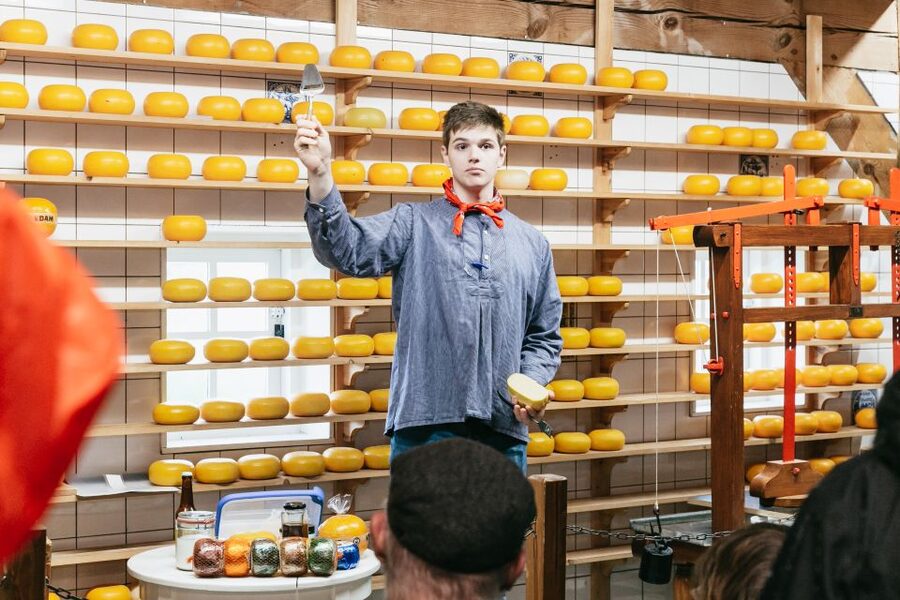 Wheels of cheese stacked to the ceiling in a cheesemonger&rsquo;s shop